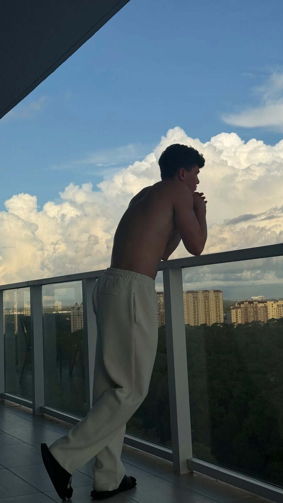 Jaxon Avery looking out from a balcony under summer clouds